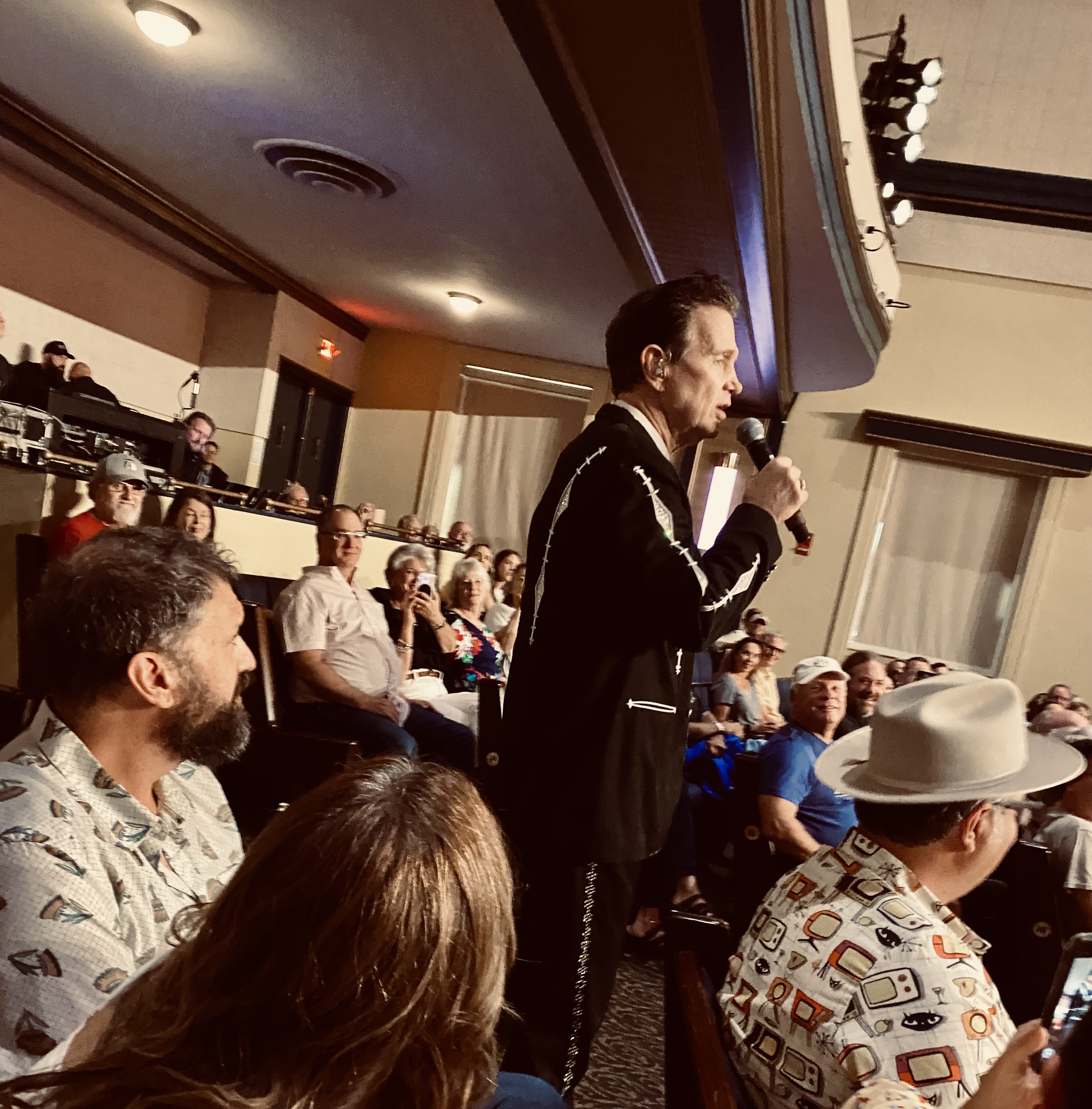 Chris Isaac walking among the audience at one of his concerts, interacting with many.